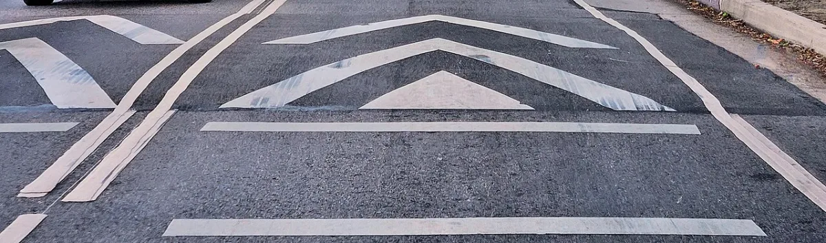 Witte pijlmarkeringen op het wegdek duiden een verkeersdrempel aan.