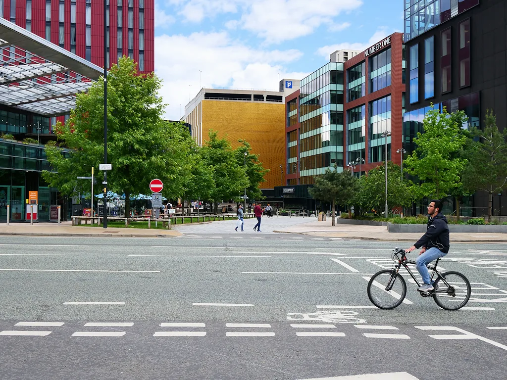 Fietser steekt een straat over tussen moderne kantoorgebouwen in het centrum van een stad
