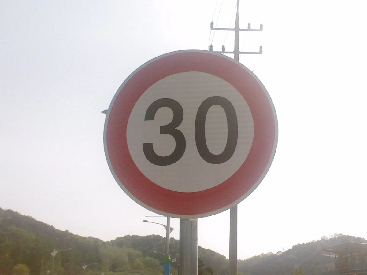 Rond verkeersbord met maximumsnelheid van 30 kilometer per uur tegen een lucht op een paal